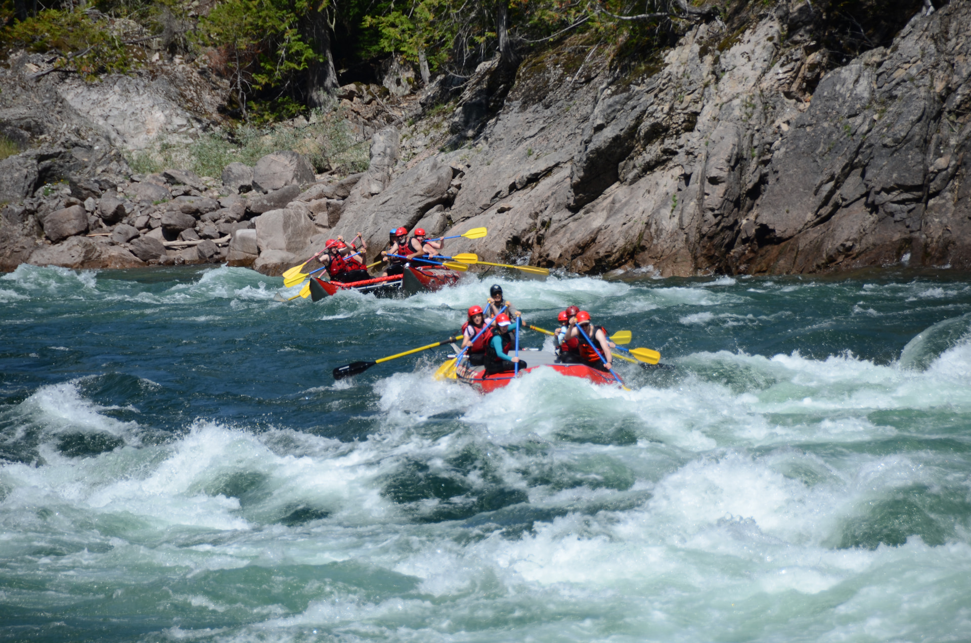 Zwei rote Rafts mit gelben Paddeln in einer Stromschnelle auf dem Clearwater River