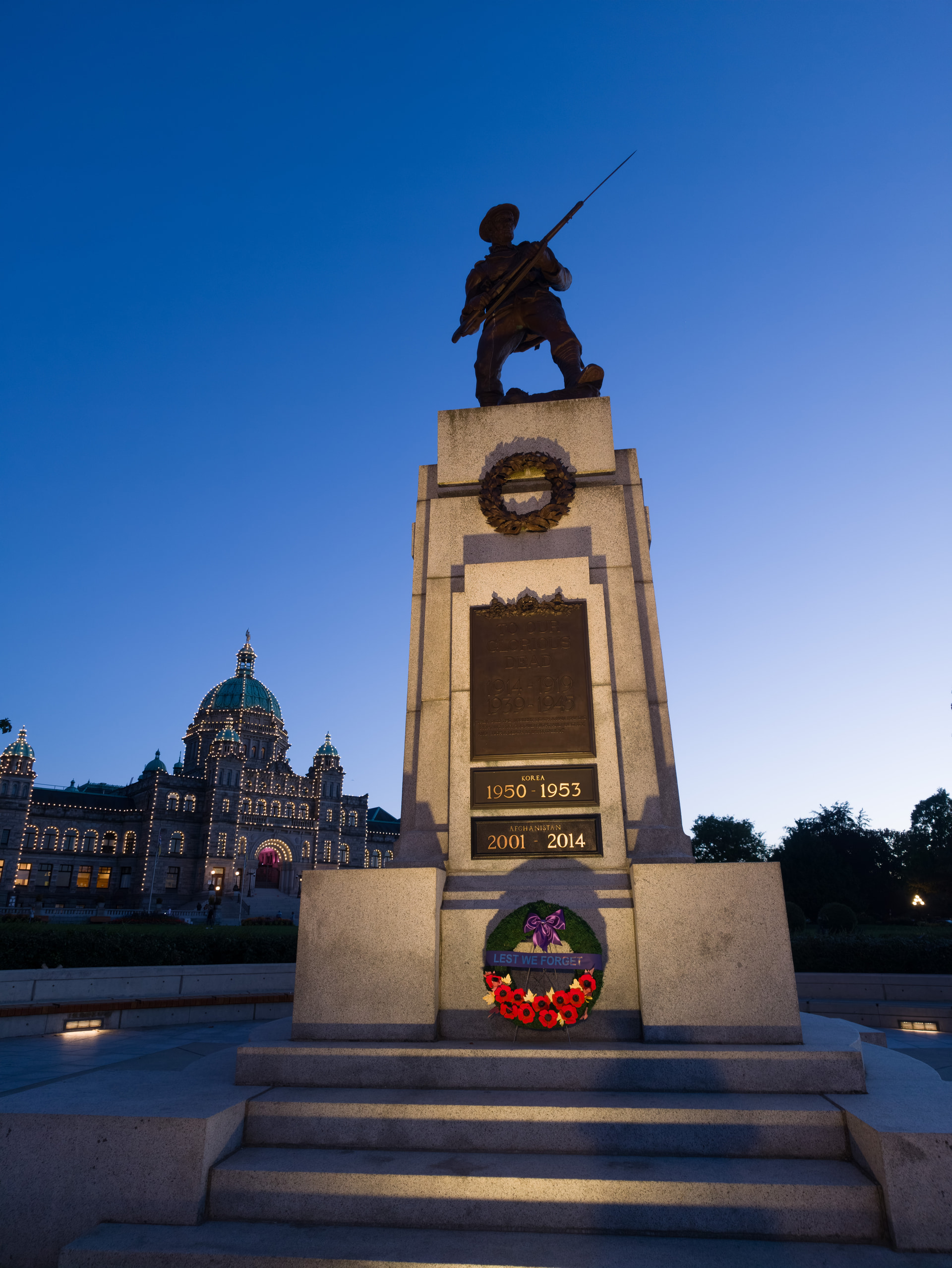Victoria Cenotaph mit Kranz vor dem beleuchteten Parlamentsgebäude in der blauen Stunde
